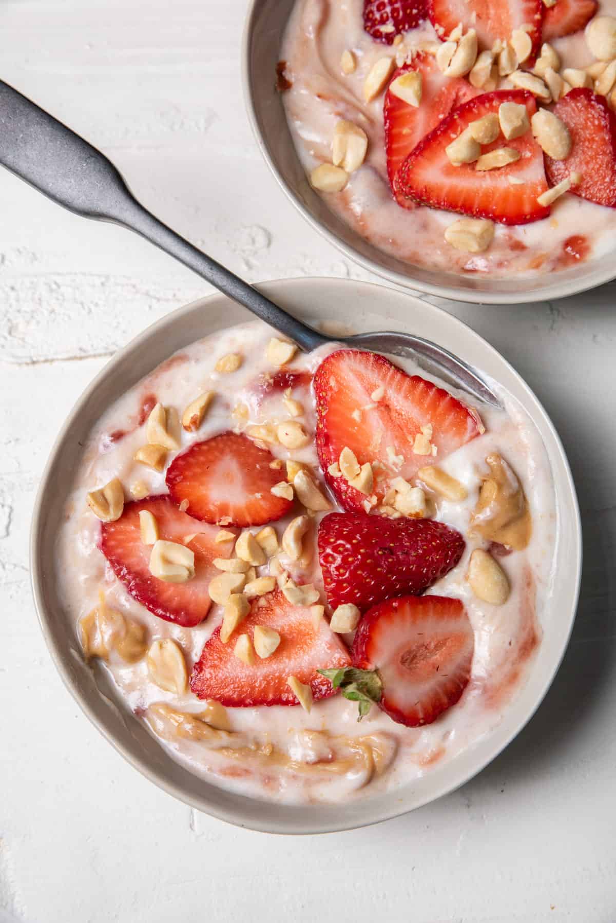 Peanut butter jelly yogurt in a bowl topped with strawberries and peanuts