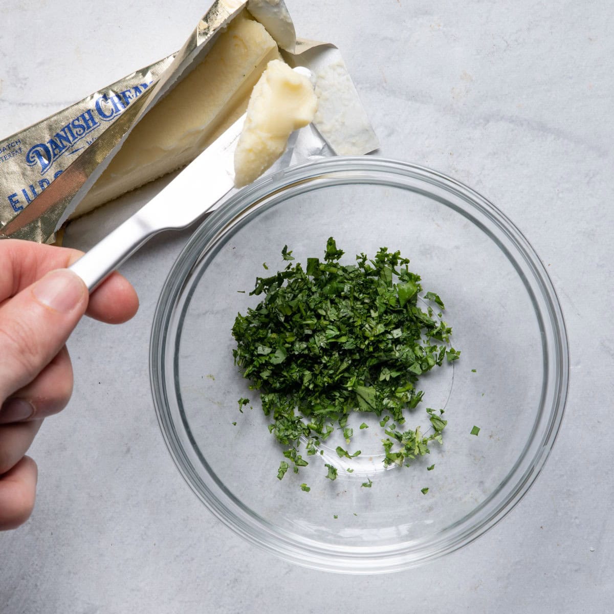 Small bowl of chopped cilantro and opened stick of room temperature butter.