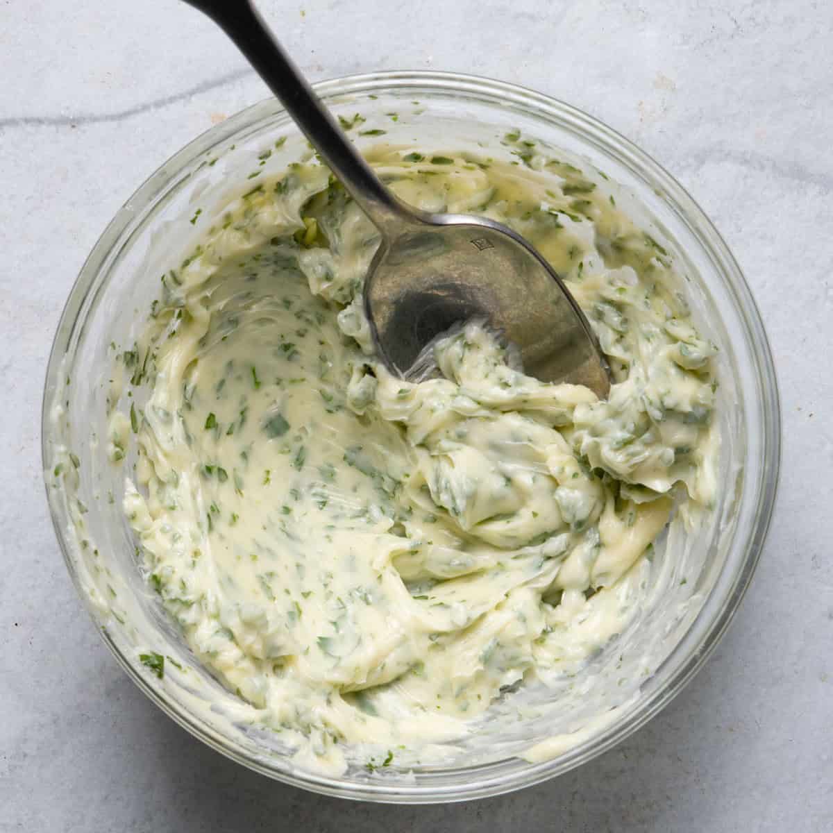 Mixing butter with cilantro in small bowl.