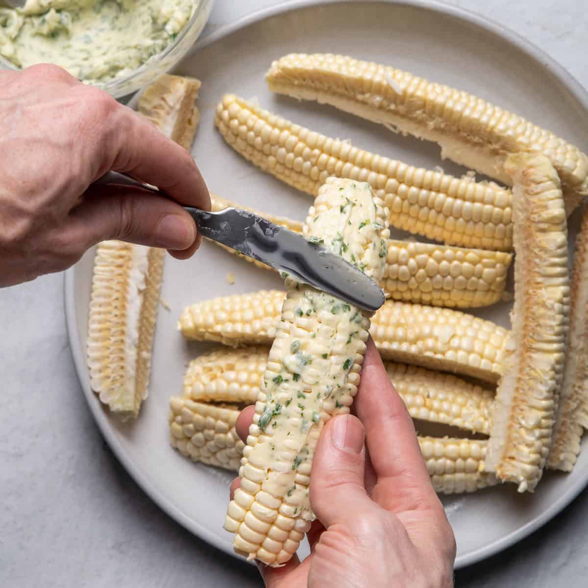 Spreading butter on one of the corn ribs.
