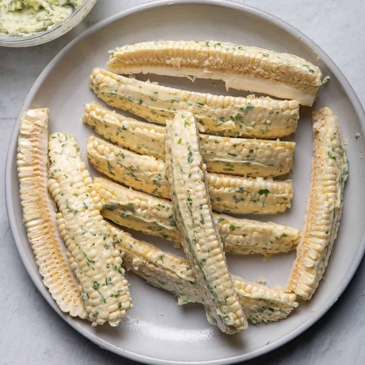 Plate of herbed butter spread on all the corn ribs.