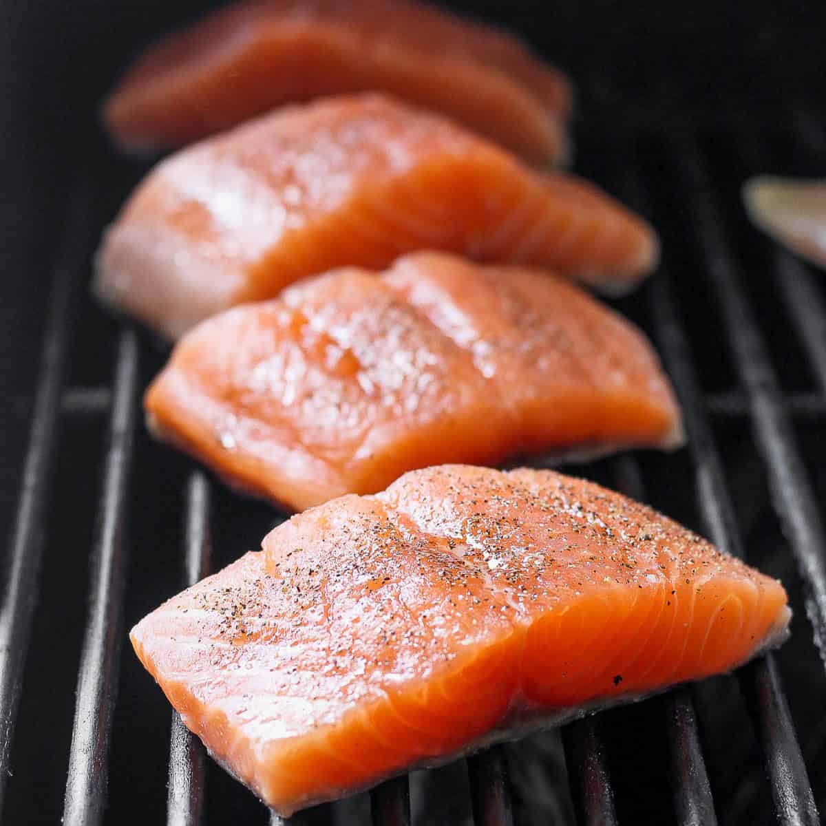 4 fillets of salmon on the grill right before ready to flip.