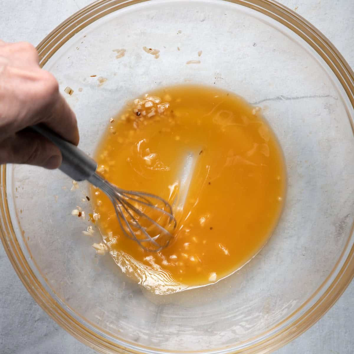 Whisking salad dressing together in large salad bowl.