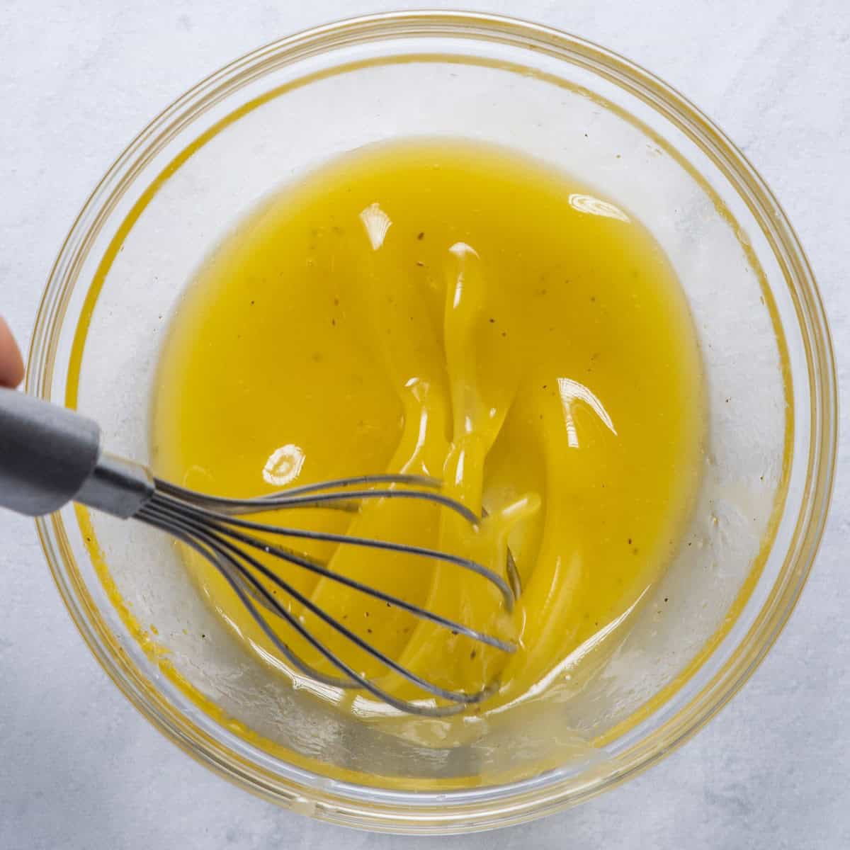 Whisking dressing next to bowl of watermelon salad.