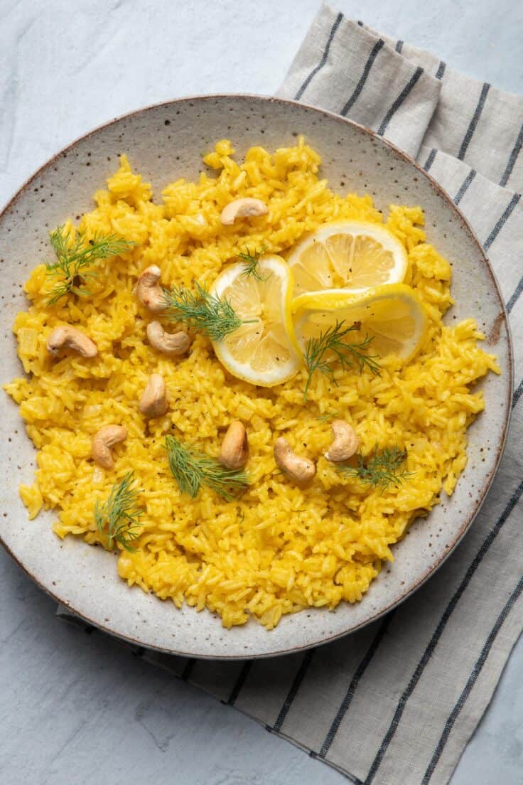 Large bowl of lemon rice garnished with dill and cashews
