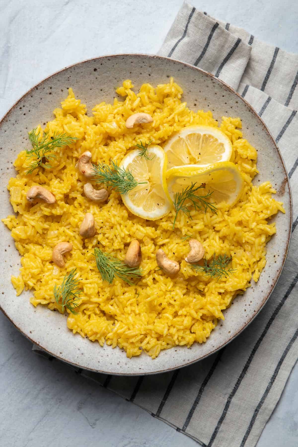Large bowl of lemon rice garnished with dill and cashews