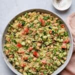 Large bowl of bulgur salad with salt and pepper in pinch bowl to it
