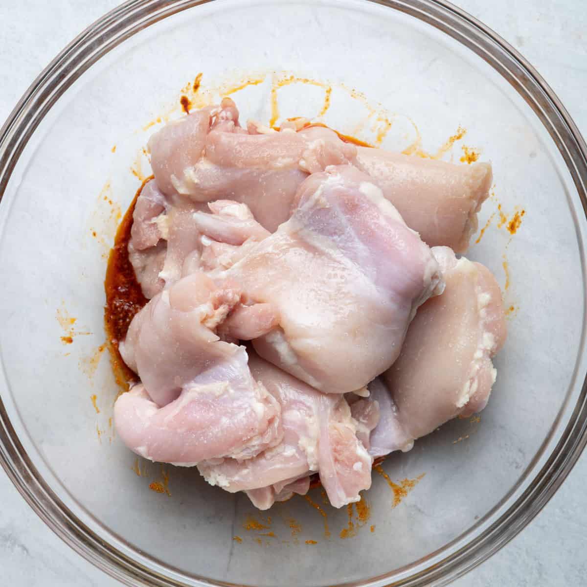 Chicken added to the bowl on top of the combined spice mix.