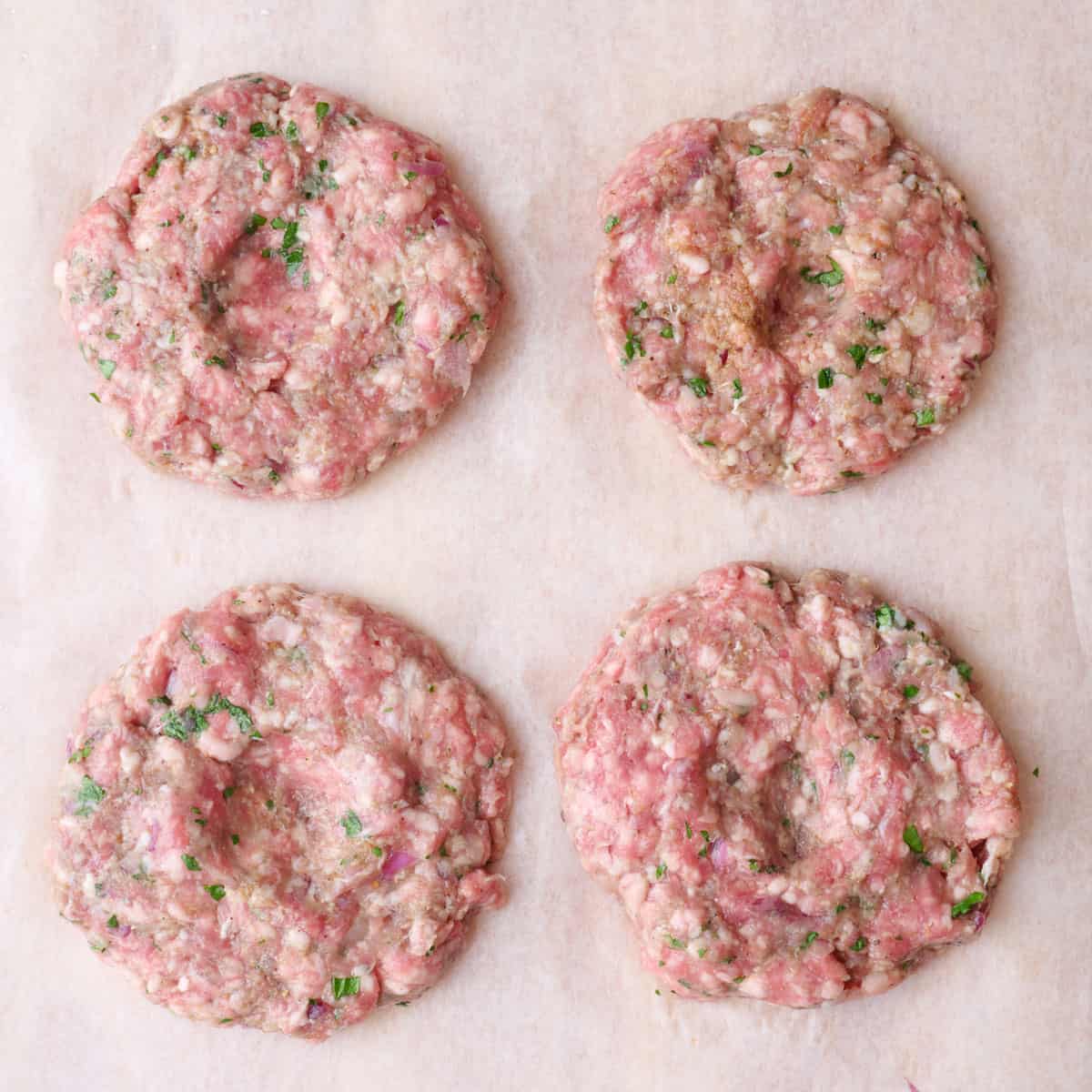 The meat shaped into four patties with a shallow indent in the center.