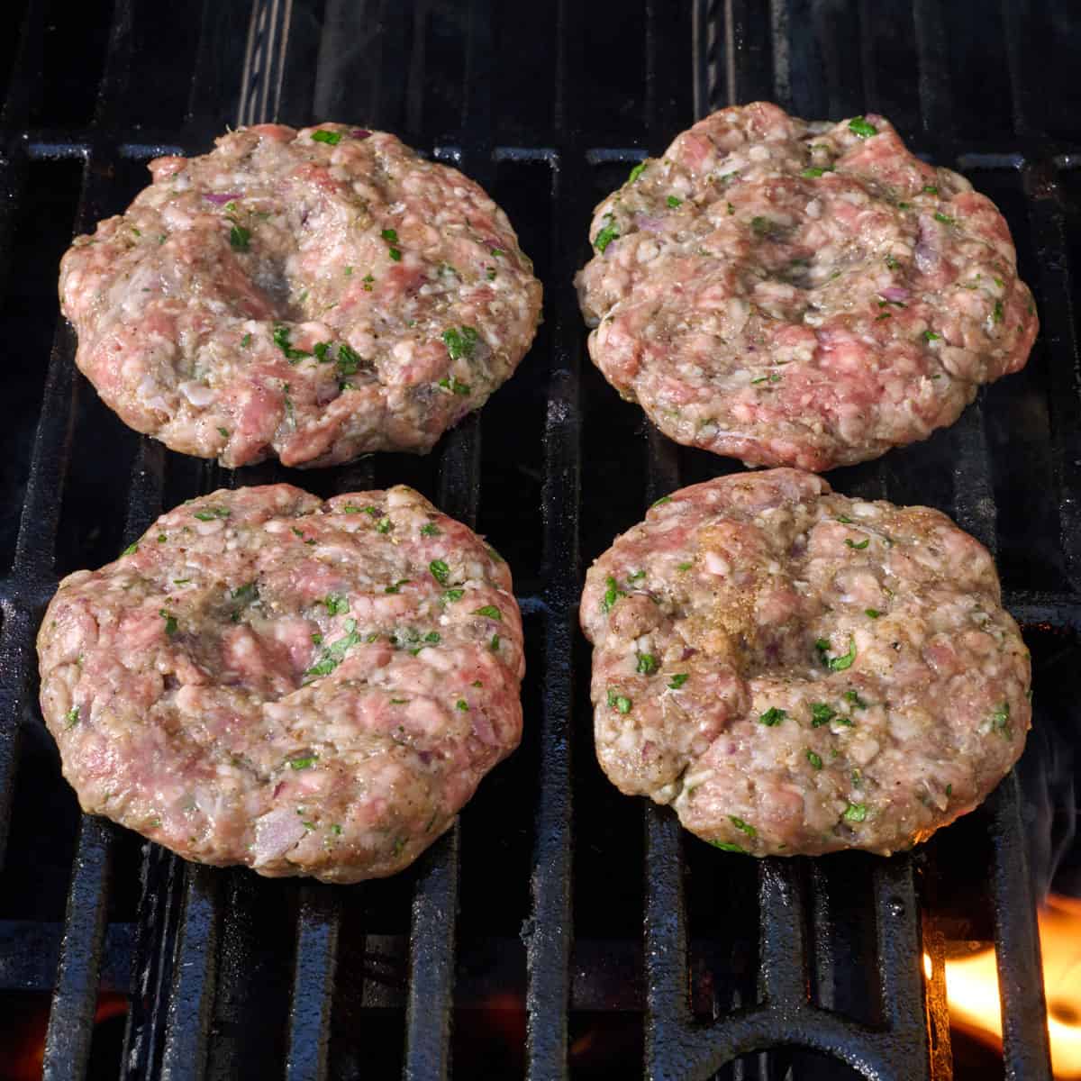 Four uncooked patties on the grill.