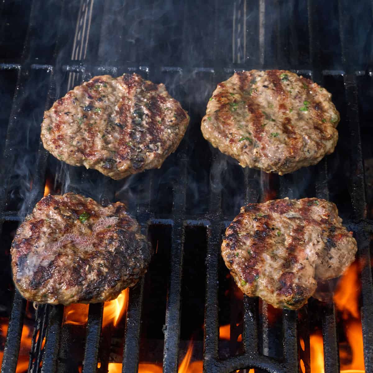 Four patties on the grill after flipping.