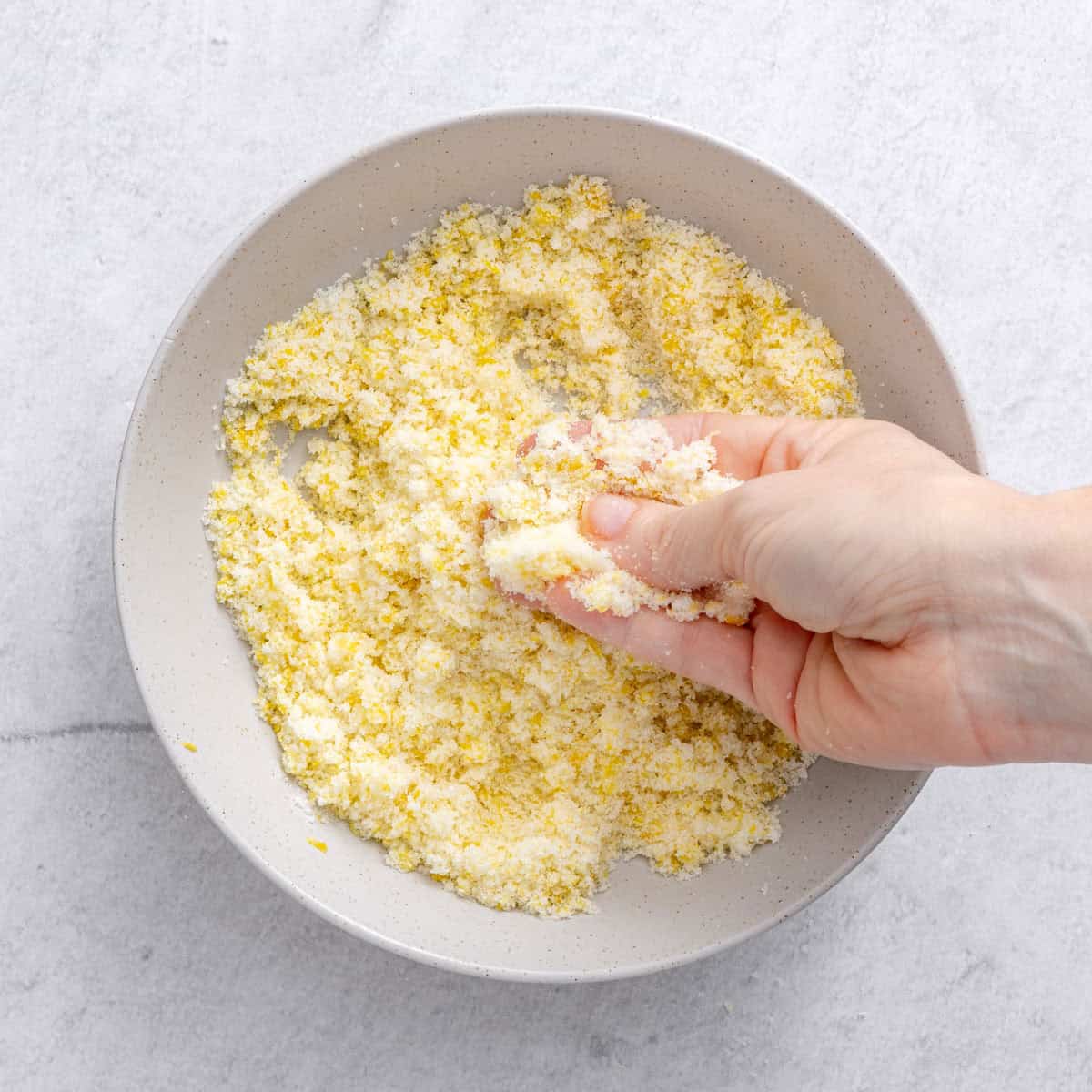 Hands rubbing them together the ingredients in the bowl.