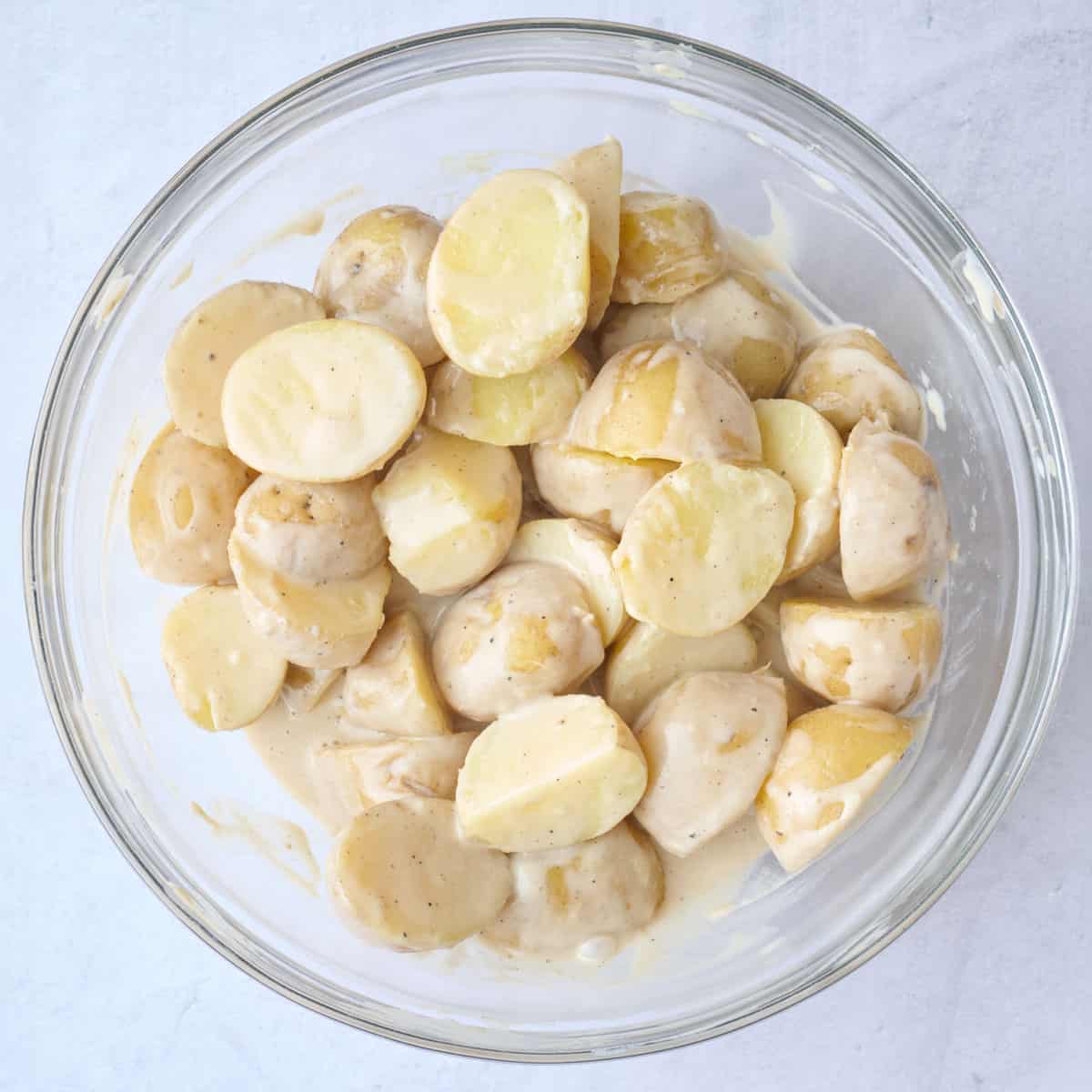 Warm cooked potatoes added to dressing mixed together.
