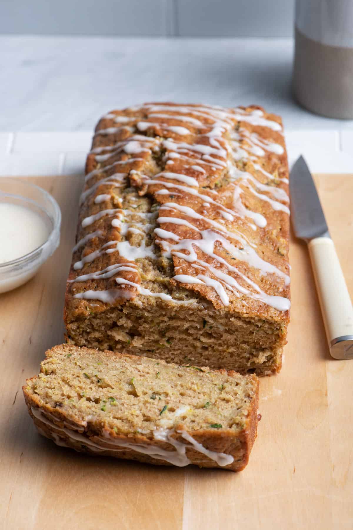 Lemon zucchini bread drizzled with glaze on cutting board