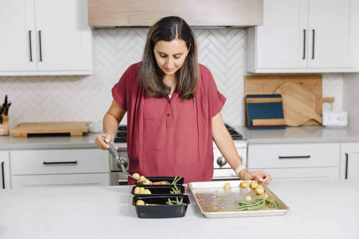 Adding cooked salmon and vegetables into meal prep containers