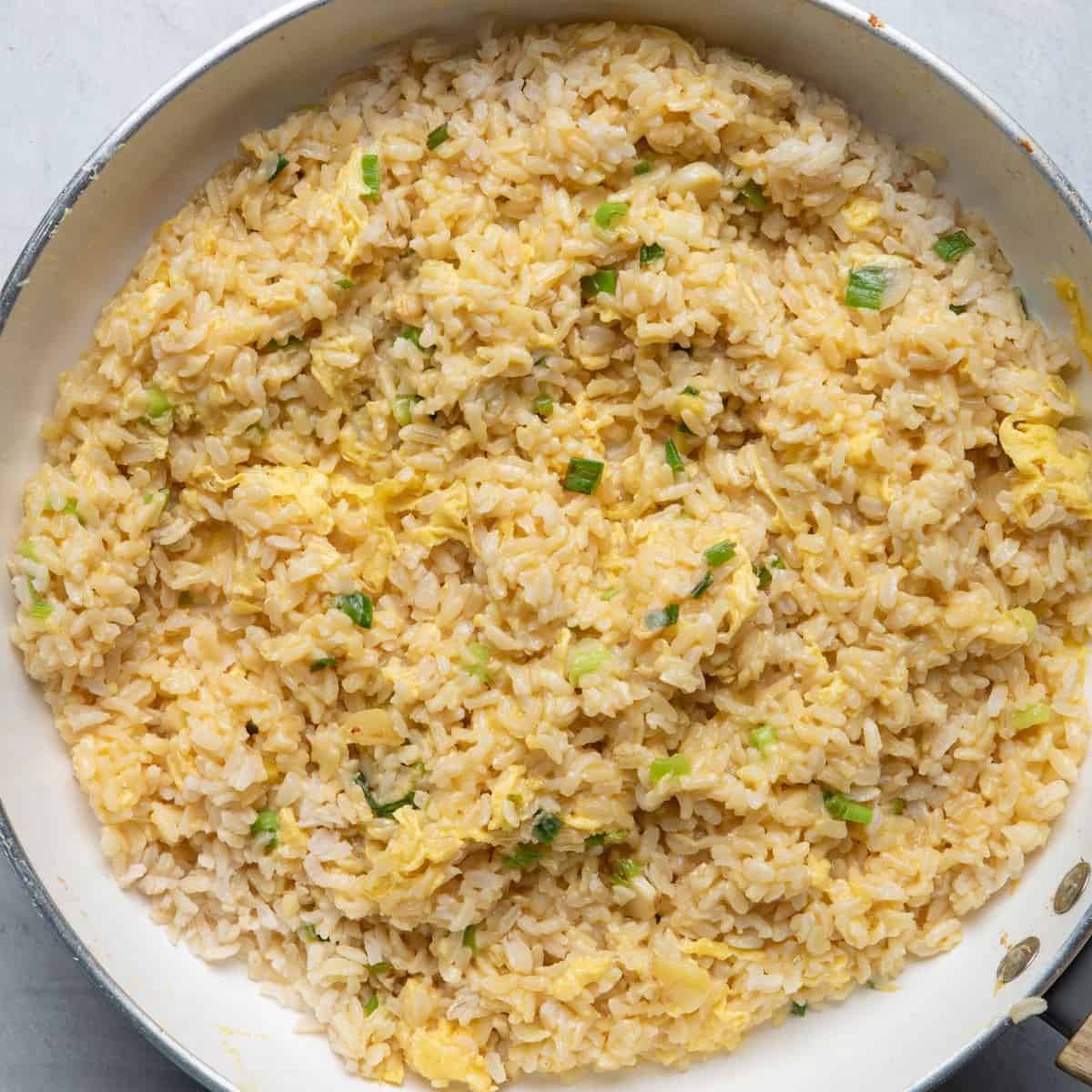 Cooked rice and eggs on top mixed with scallions, garlic and ginger.