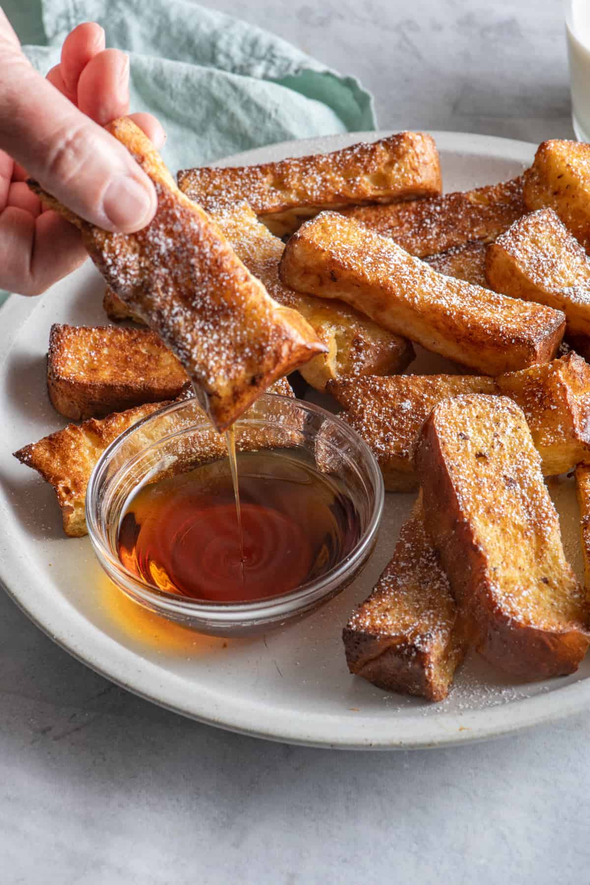 Air fried french toast dunking into bowl of maple syrup