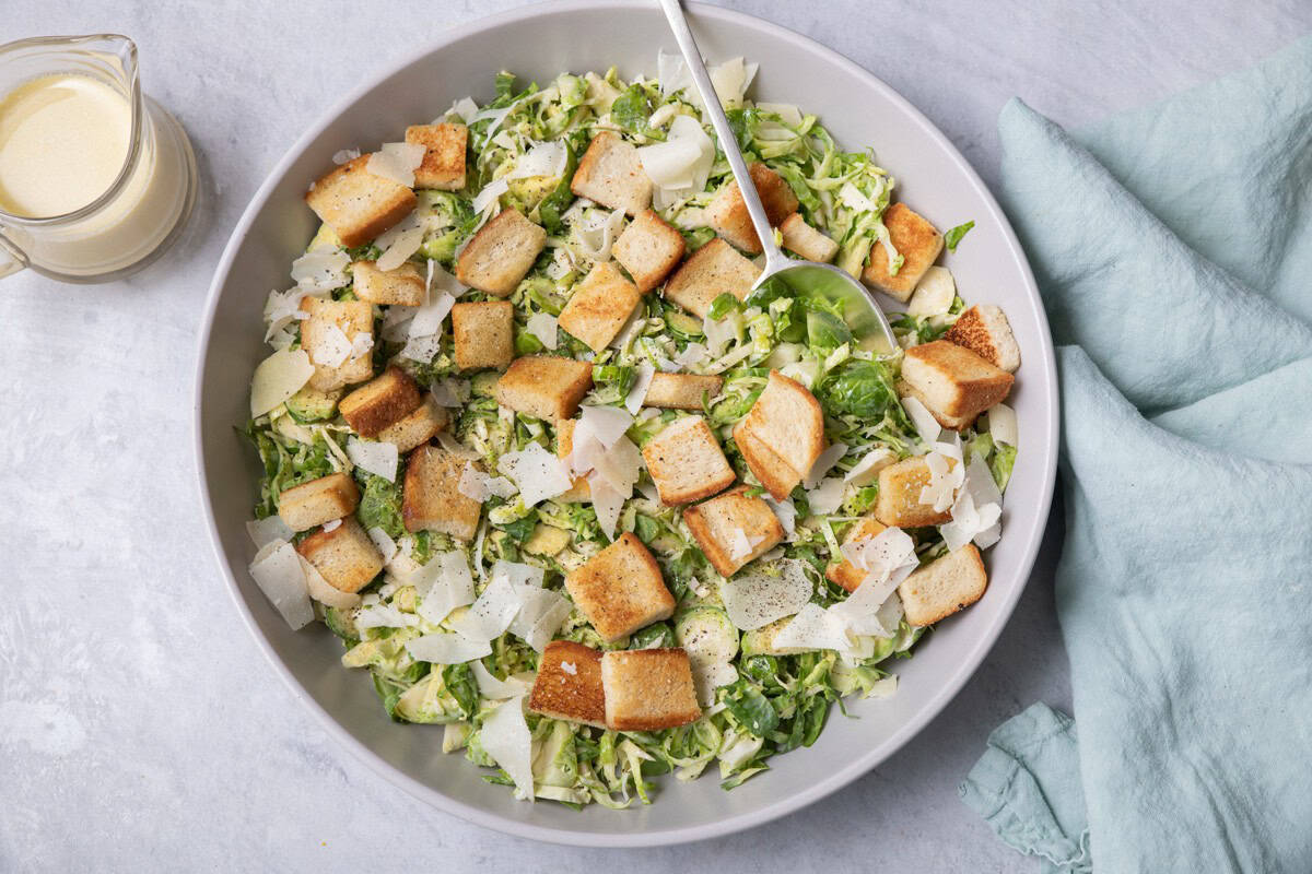 Large bowl of the salad with croutons and parmesan cheese with spoon or tongs for serving in the bowl.