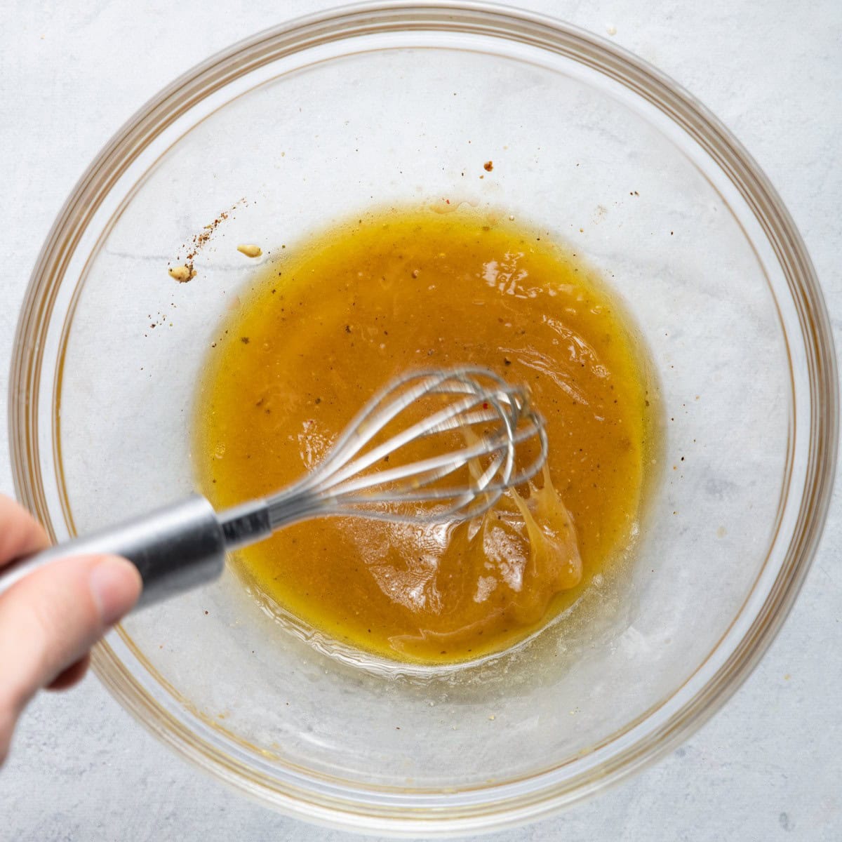 Whisking salad dressing in large bowl.