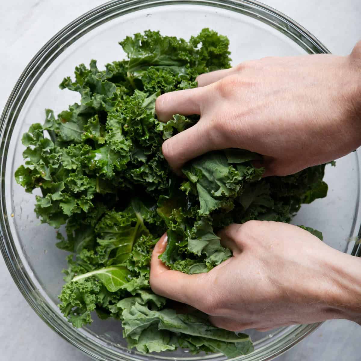 Hands massaging kale.