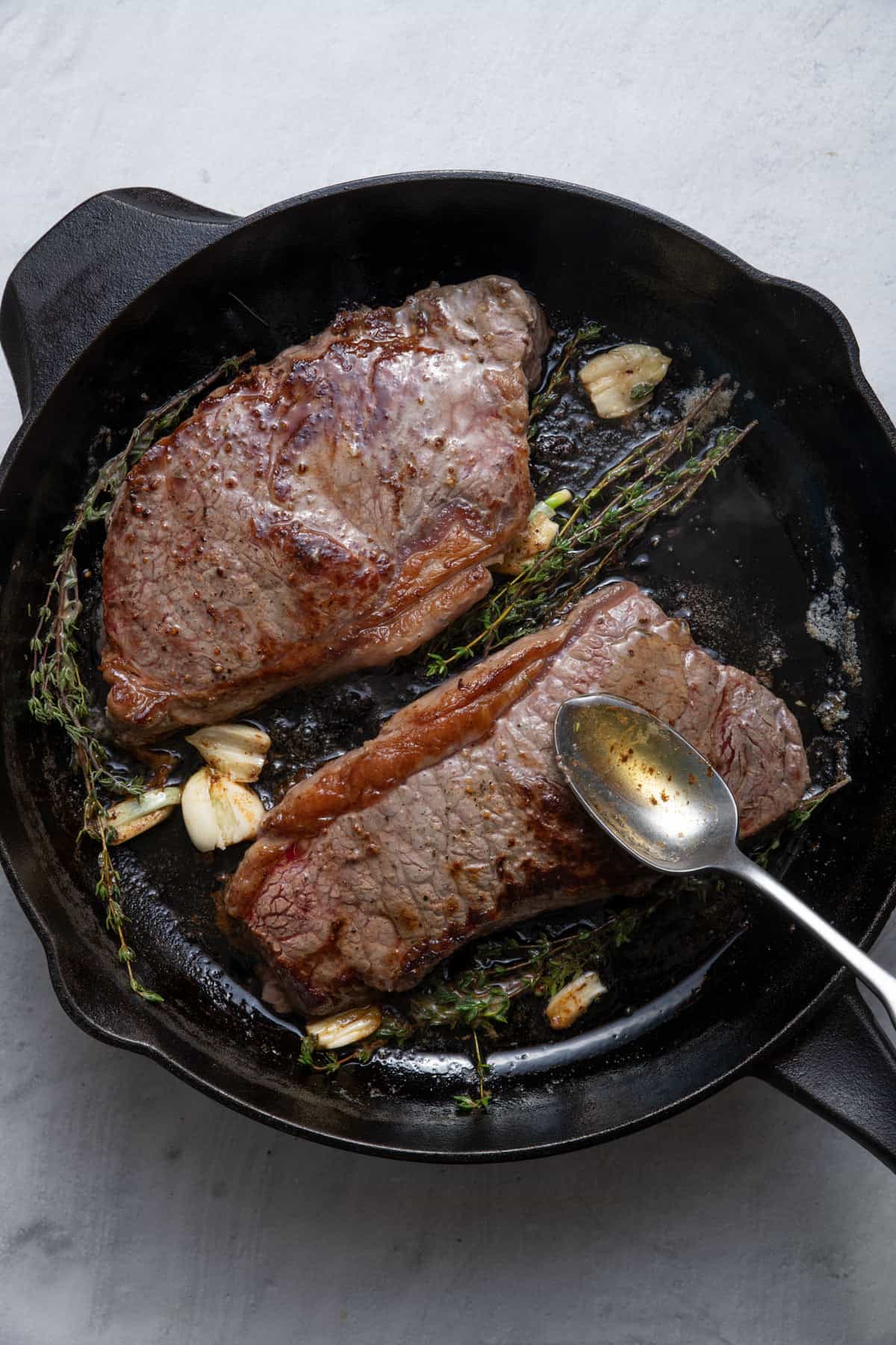 Spoon basting the steak in the skillet
