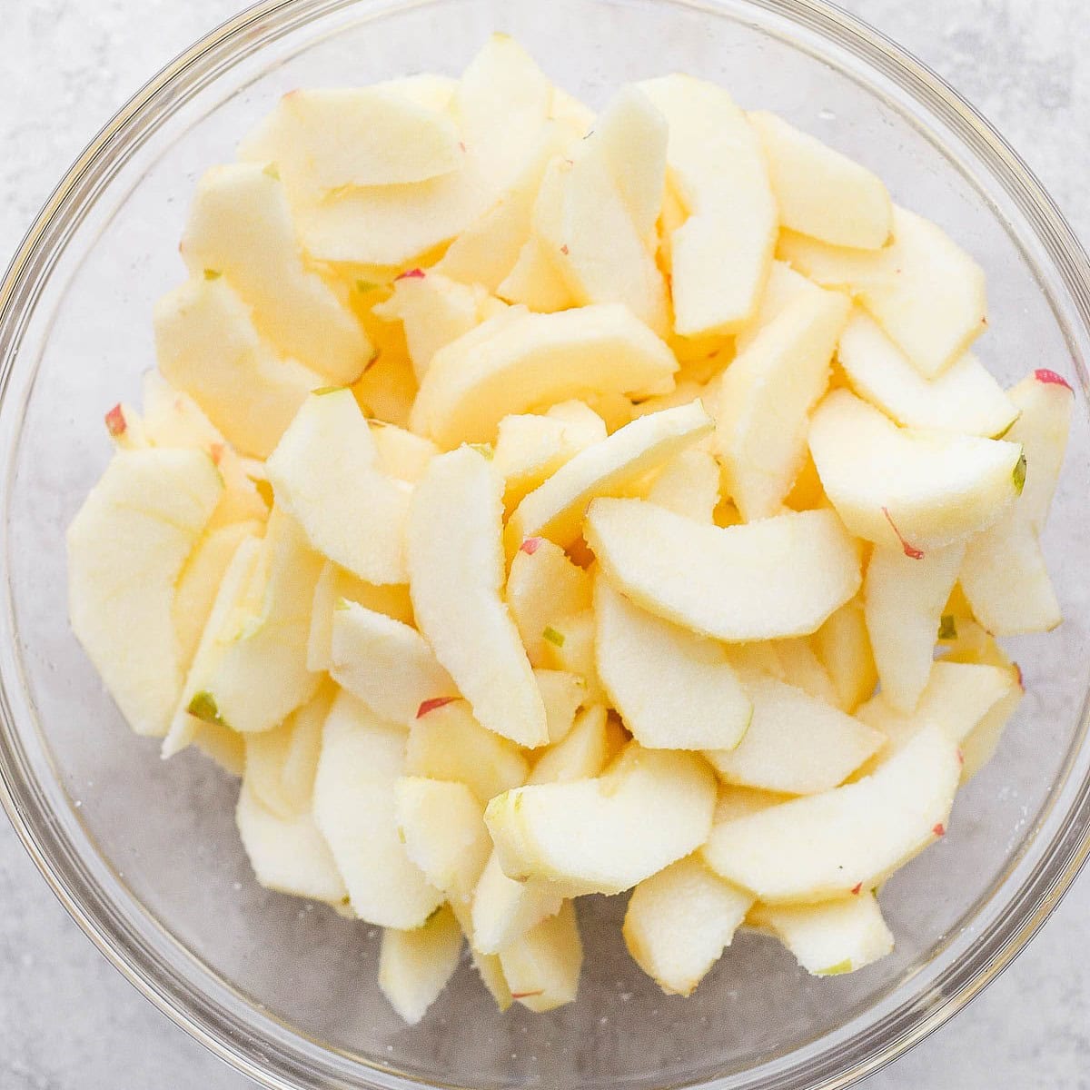 Bowl of apples, sugar and lemon juice mixed together.