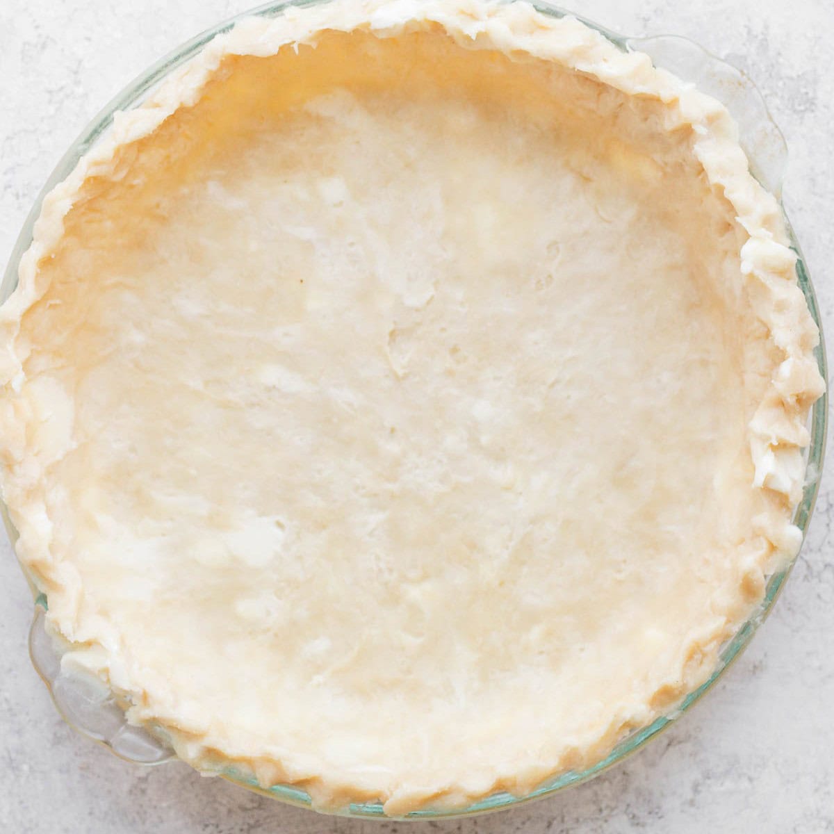 Pie dough pressed into glass pie dish.