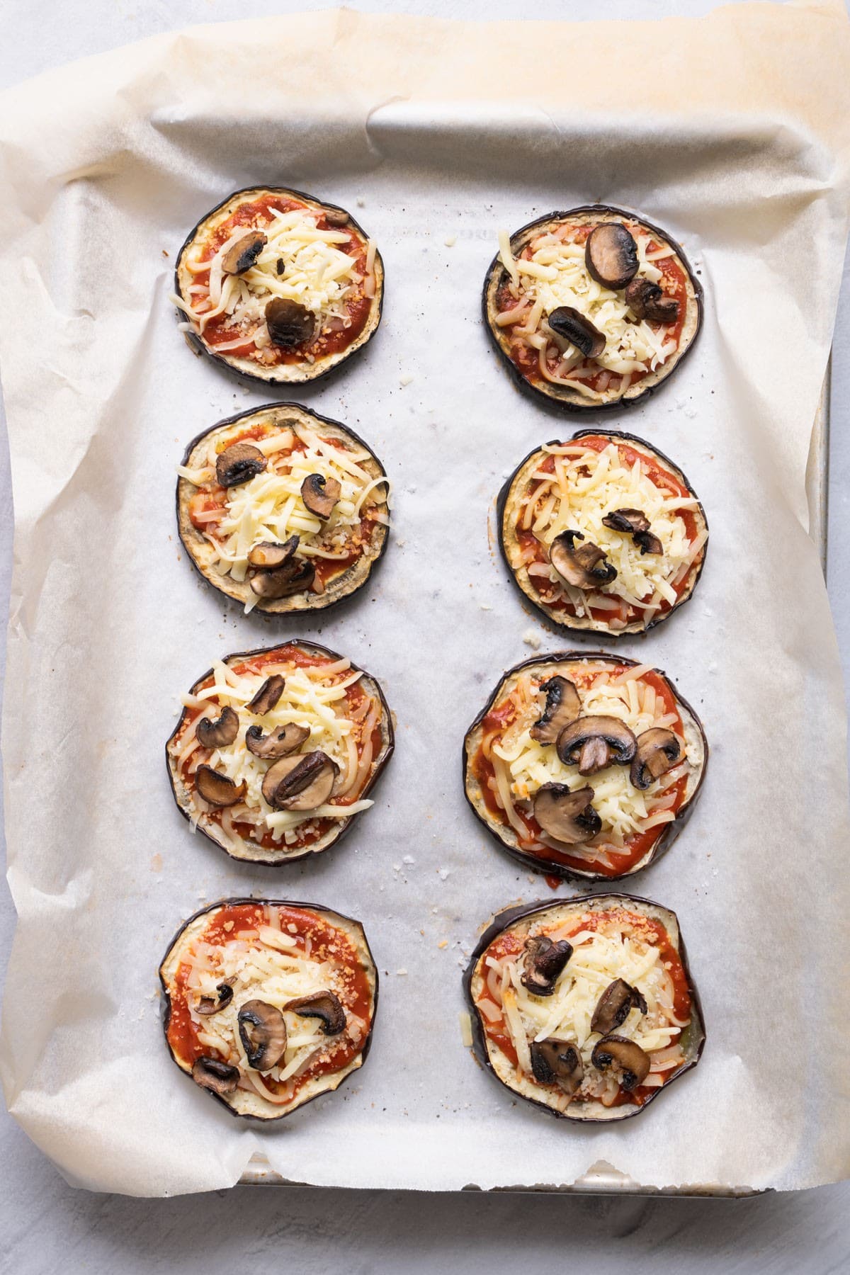 Eggplant with sauce, mozzarella, parmesan and mushroom added on top.