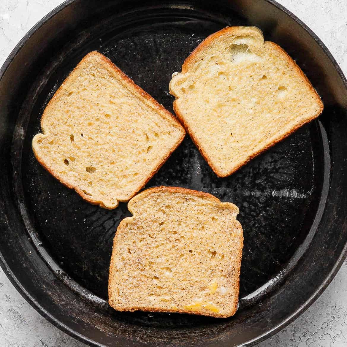 Three pieces of bread in a skillet.