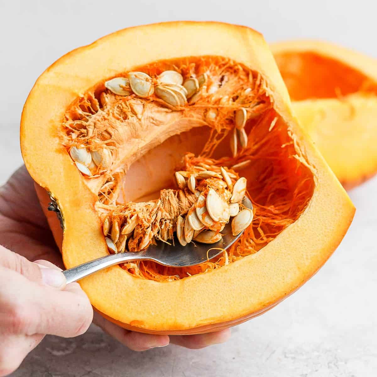 Scoop out seeds from pumpkin halves.