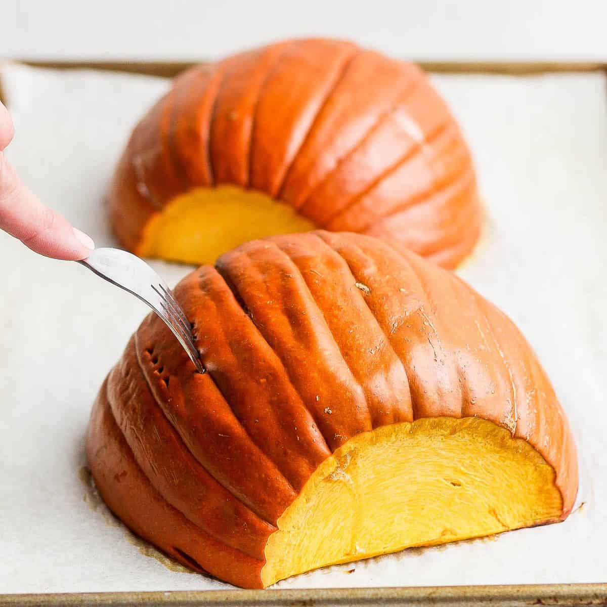 Two pumpkin halves after roasting showing softened skin.
