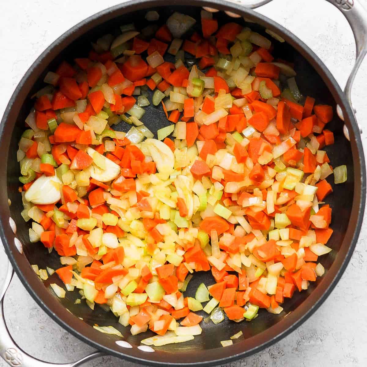 Onions, carrots, celery and garlic cooked in pot.
