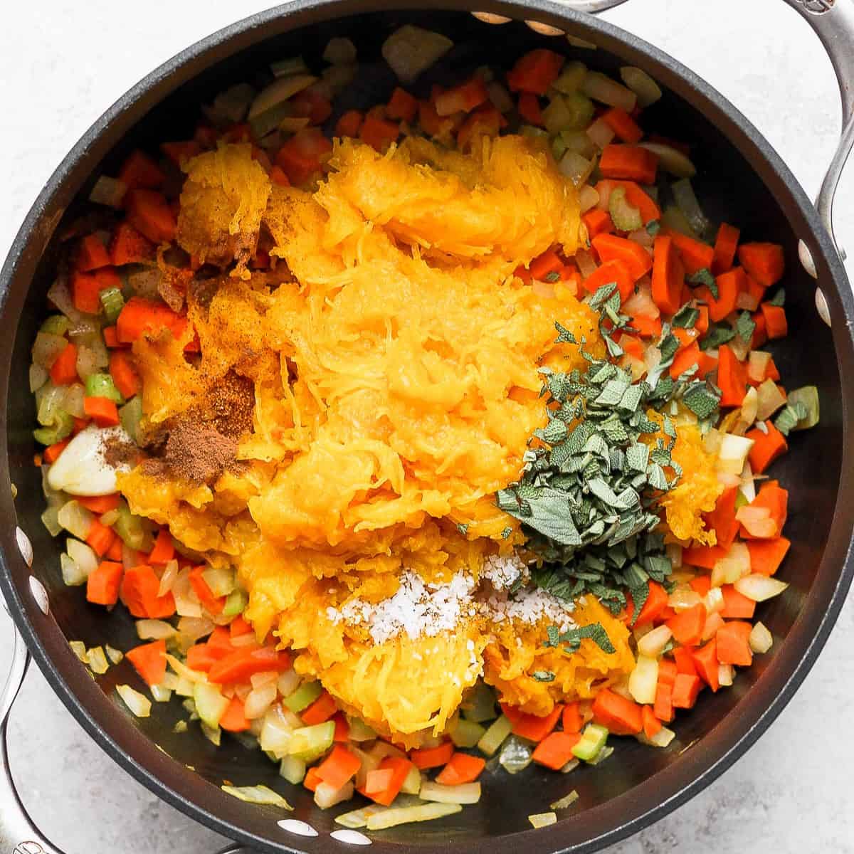 Pumpkin flesh on top of cooked vegetables along with seasoning.