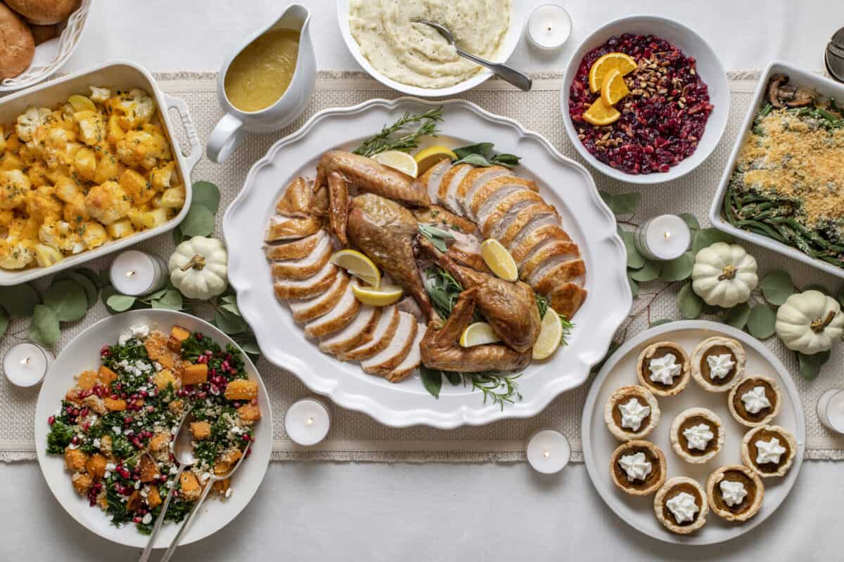 Thanksgiving dinner table with carved turkey, sides and dessert