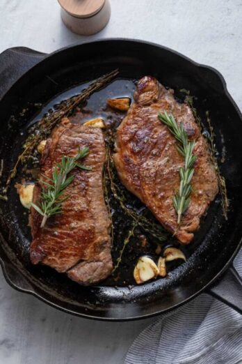 Steak cooked in cast iron skillet with rosemary and garlic