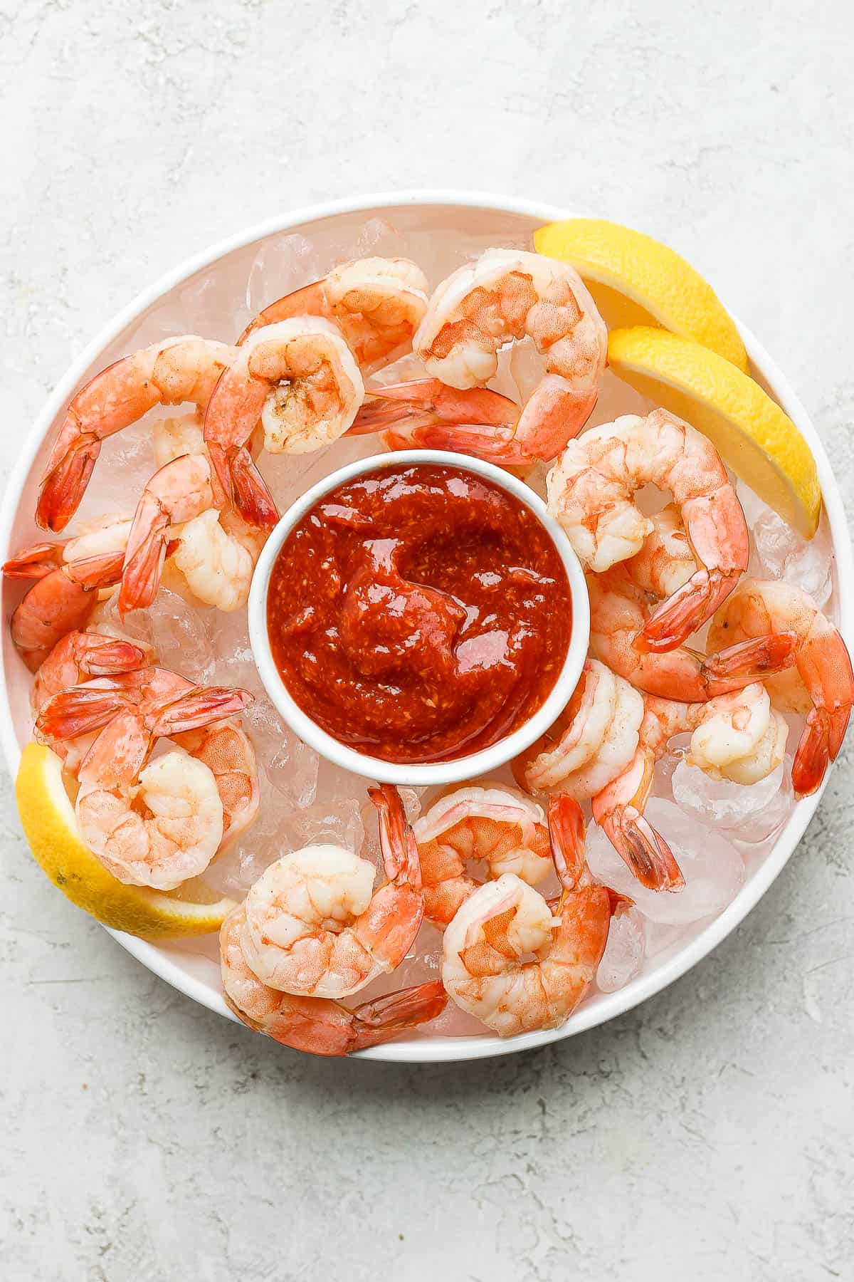 Shrimp cocktail served with the sauce over bed of ice with lemon wedges