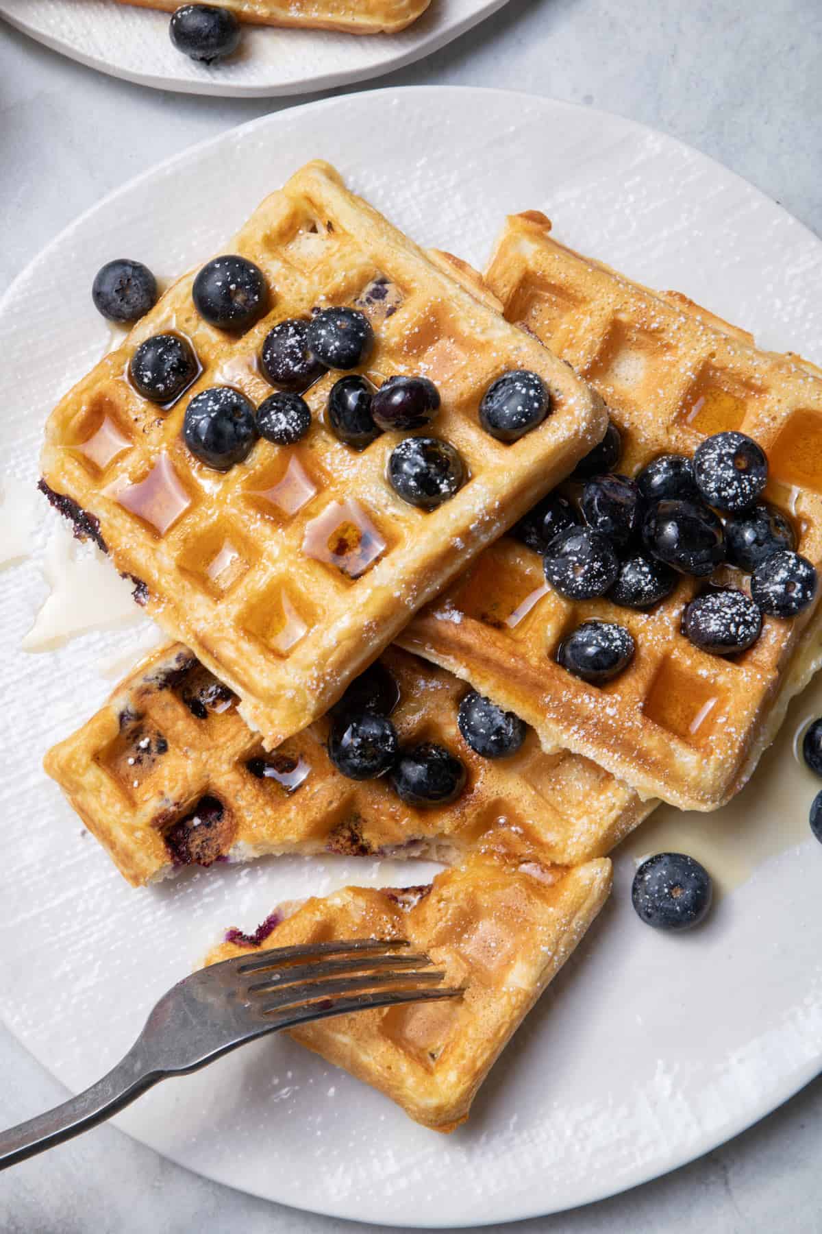 Fork cutting into blueberry yogurt waffles