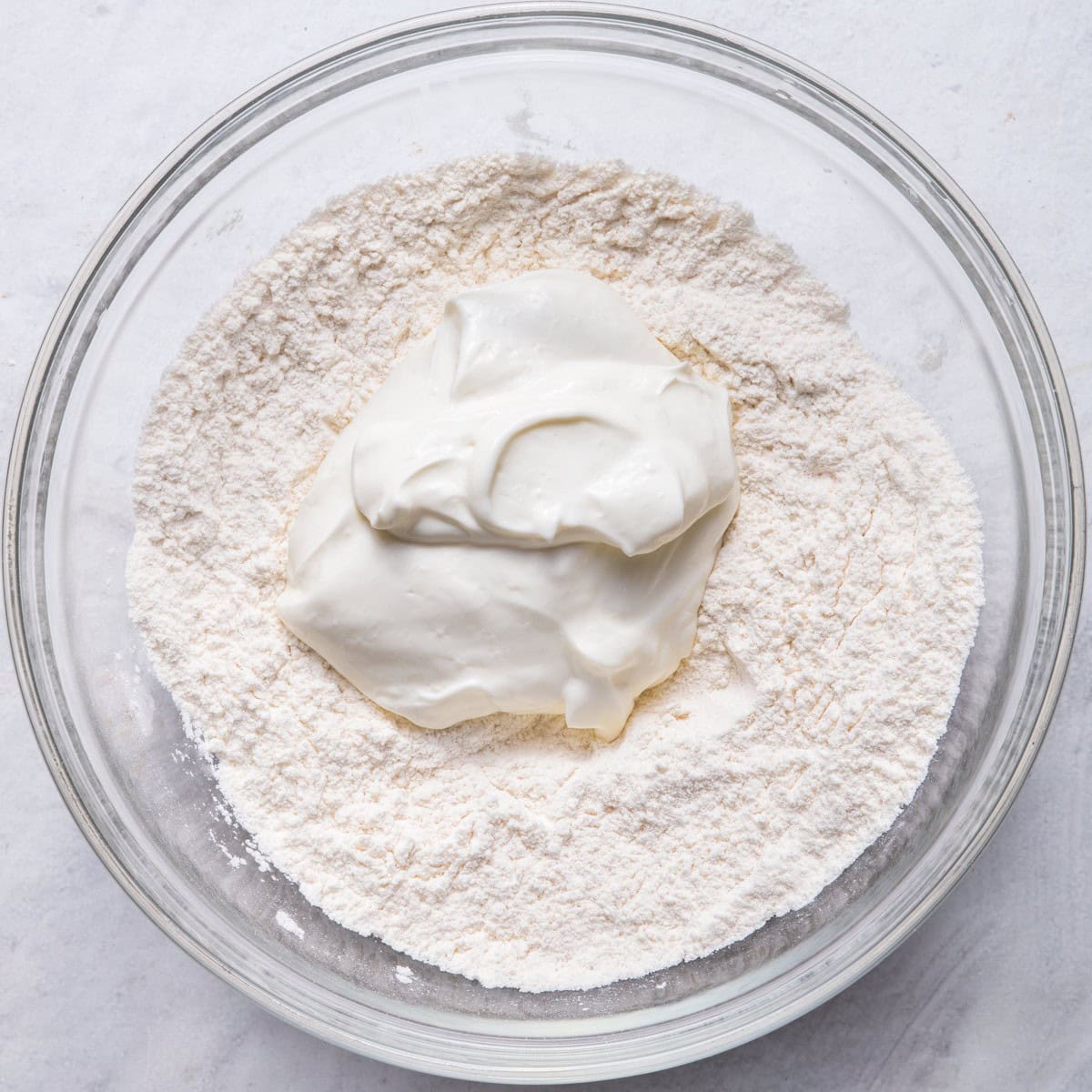 Flour mixture in bowl with greek yogurt in middle.