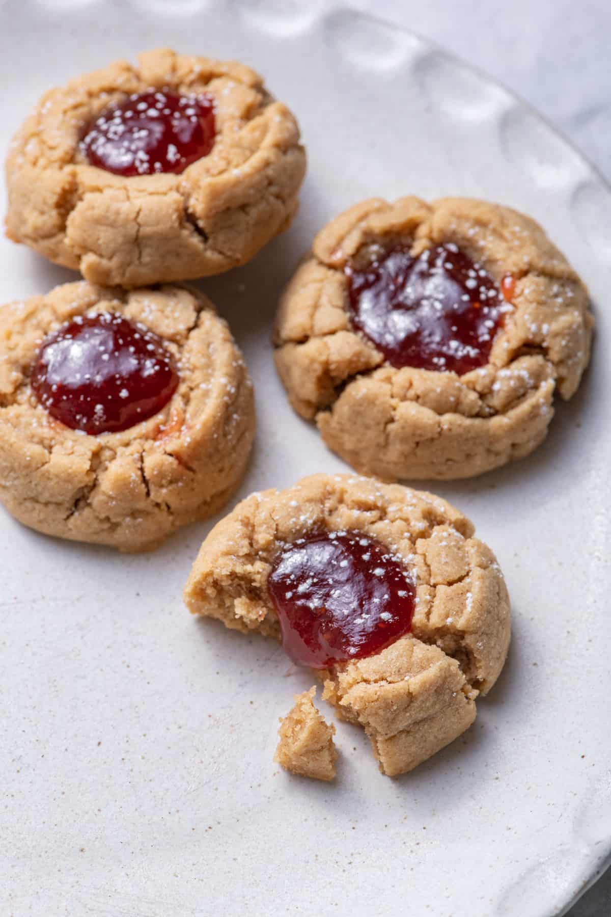 Close up shot of the peanut butter jam thumbprint cookies with bite taken out of one cookie