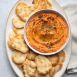 Roasted red pepper hummus on a platter served with small naan dippers