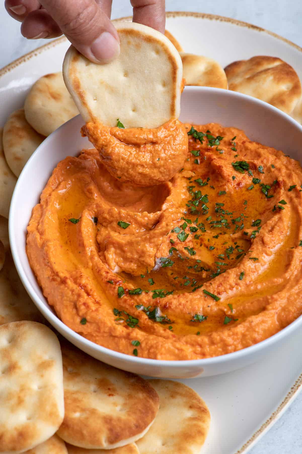 Naan bread dipping into roasted red pepper hummus