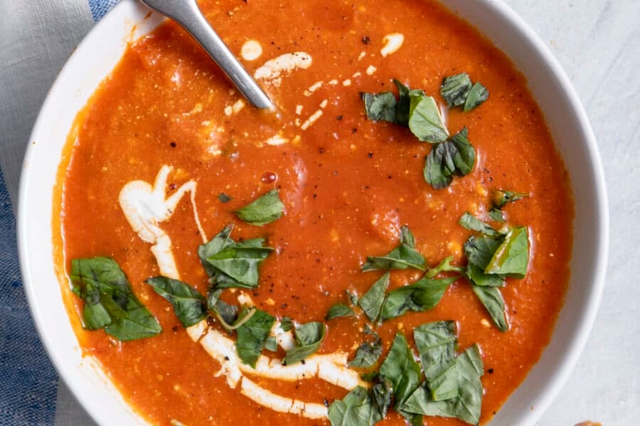 bowl of Roasted red pepper soup bowl with baguette next to it