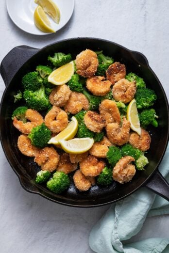Sesame shrimp with broccoli and lemon wedges on skillet