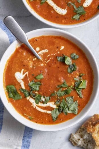 bowl of Roasted red pepper soup bowl with baguette next to it