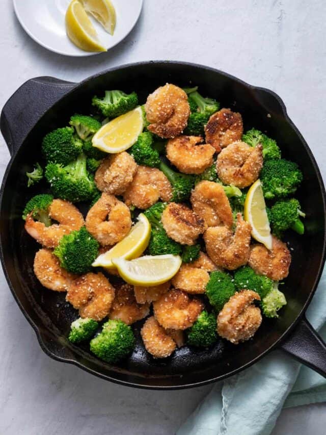 Sesame shrimp with broccoli and lemon wedges on skillet