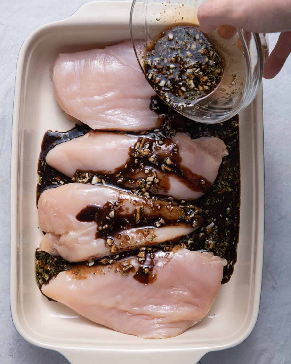 Pouring the marinade on top of the chicken.
