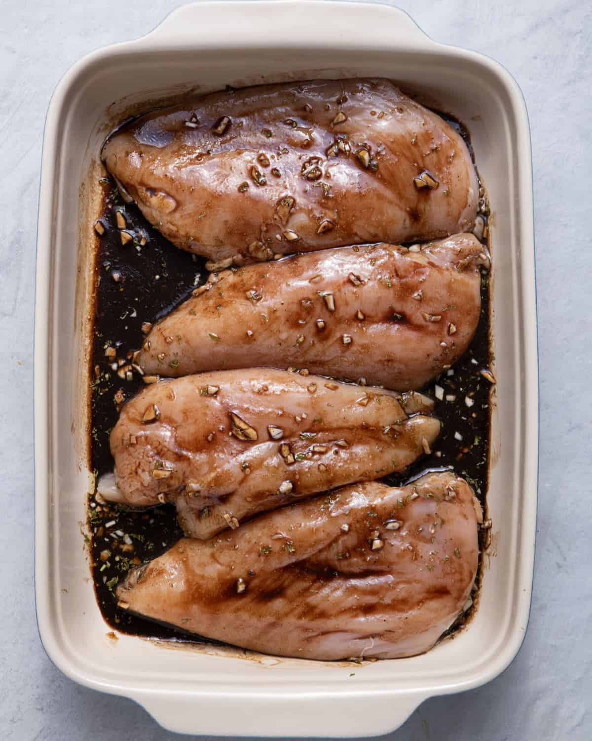 Chicken well coated in the marinade in dish.