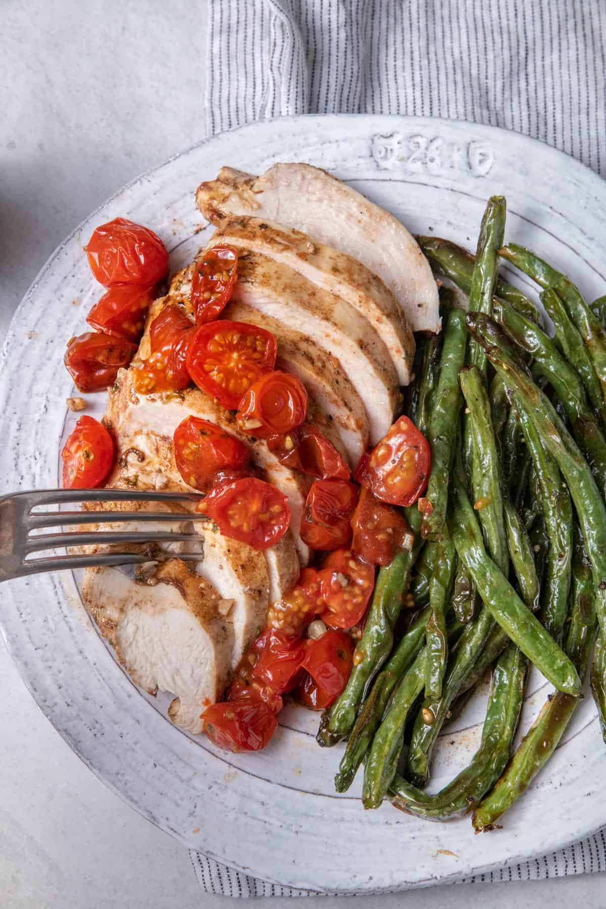 Plate of honey balsamic baked chicken sliced with cherry tomatoes on top