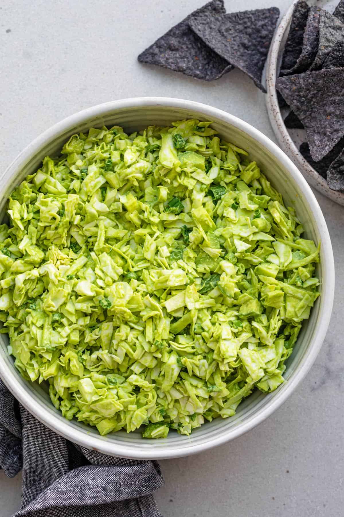 Bowl of green goddess salad served with tortilla chips on the side