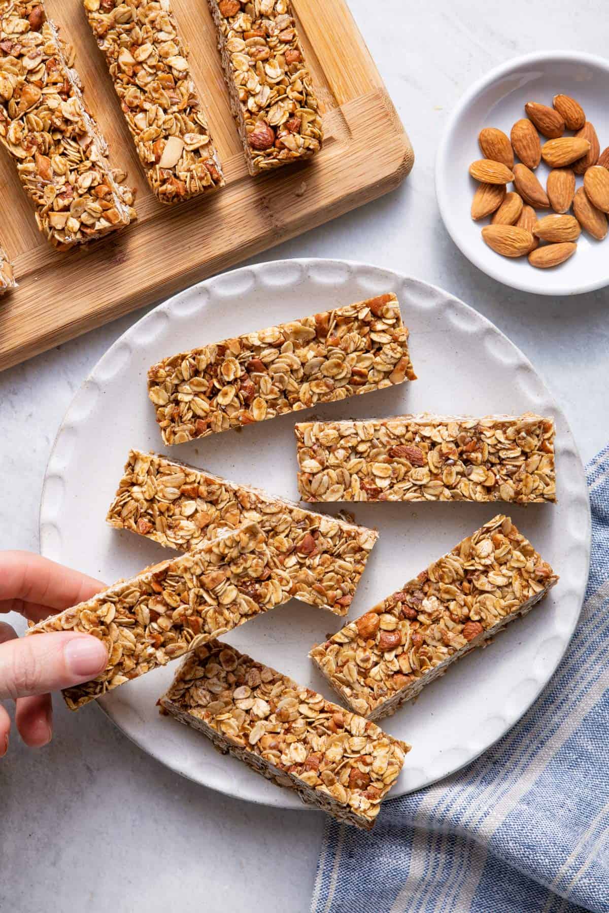 Honey oat granola bars on a plate with hand grabbing one